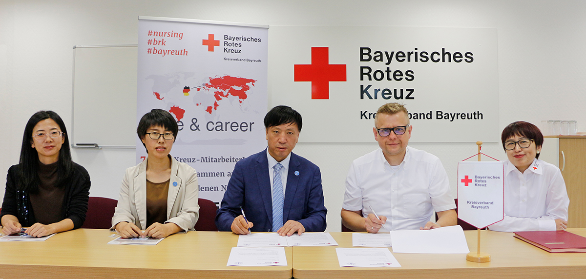 Vizerektor Yumin Zhao, Zhaoyan Duan (Vertreterin des Pflegeinstituts, Abteilung Bildung) und Litong Chen (Mitarbeiterin der Abteilung für internationalen Austausch und Zusammenarbeit), wurde von Markus Ruckdeschel, Geschäftsführer des BRK-Kreisverbandes Bayreuth, und Chen Chen, Inhaberin der Stabsstelle für internationales Recruiting, bei der Unterzeichnung der Absichtserklärung.